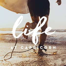 A man with a surfboard running into the ocean at Capricorn Beach, Yanchep.