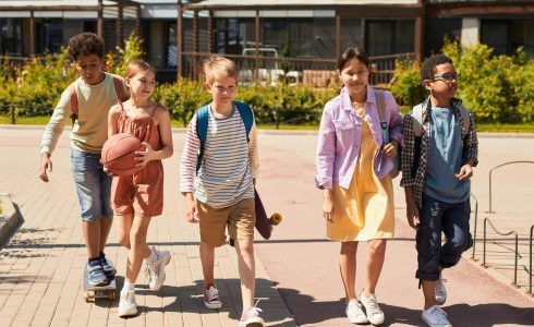 Group of children enjoying school holiday fun in Yanchep, walking with a basketball and skateboard on a sunny day